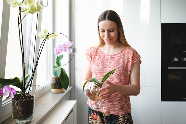 Jolie femme tenant dans les mains une boîte d'eau avec une plante d'orchidée