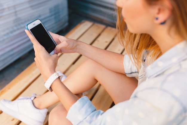 Jolie femme tenant le téléphone dans les mains tout en touchant l'écran