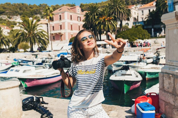 Jolie femme en vacances en Europe au bord de la mer lors d'une croisière à prendre des photos à la caméra