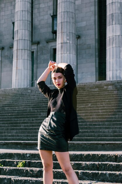 Une jolie femme en vêtements de mode avec les mains sur sa tête