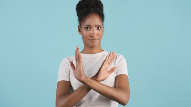 Photo gratuite jolie fille afro-américaine avec les mains croisées ne montrant en toute confiance aucun geste devant la caméra sur fond coloré