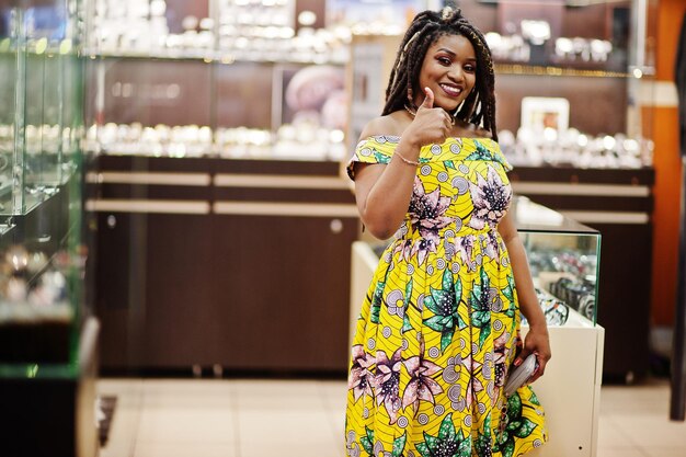 Jolie fille afro-américaine de petite taille avec des dreadlocks porter à la robe jaune colorée sur le magasin de montres au centre commercial