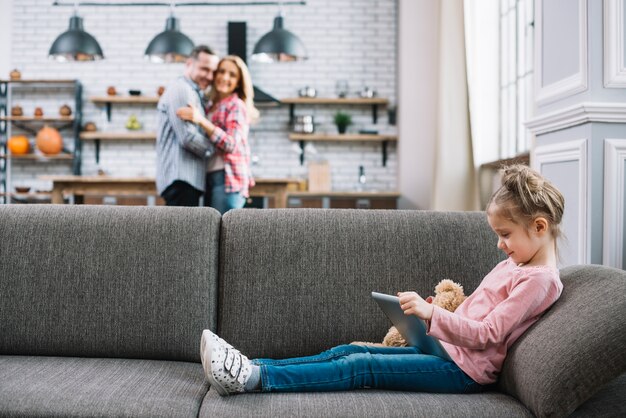 Photo gratuite jolie fille à l'aide d'une tablette numérique assis sur un canapé