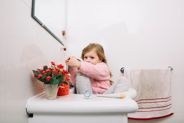 Jolie fille assise dans le lavabo de la salle de bain