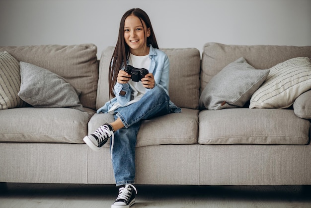 Photo gratuite jolie fille assise sur un entraîneur et jouant à des jeux vidéo sur un joypad