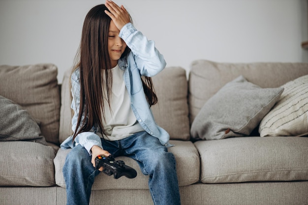 Jolie fille assise sur un entraîneur et jouant à des jeux vidéo sur un joypad