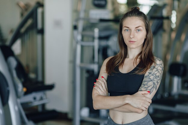 Jolie fille athlétique se dresse sur le mur des simulateurs dans la salle de gym. mode de vie sain.