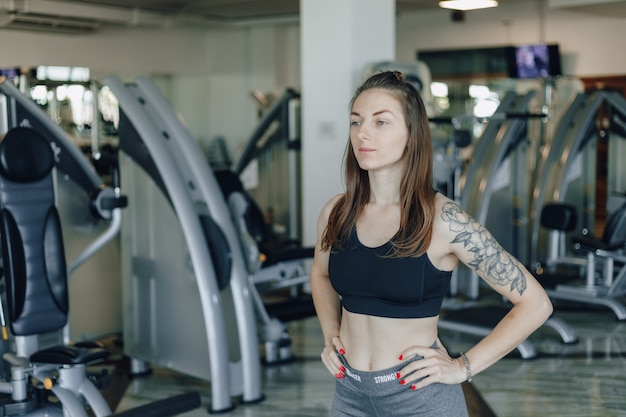 Jolie fille athlétique se dresse sur le mur des simulateurs dans la salle de gym. mode de vie sain.