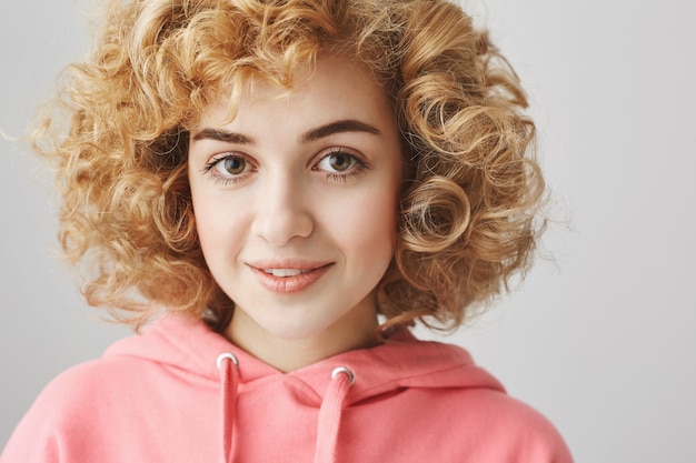 Jolie fille aux cheveux bouclés souriant timide