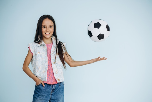 Jolie fille avec ballon de football au studio