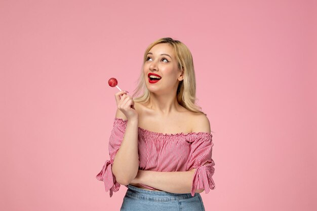 Jolie fille belle jeune femme avec du rouge à lèvres en chemisier rose tenant une sucette rose ronde