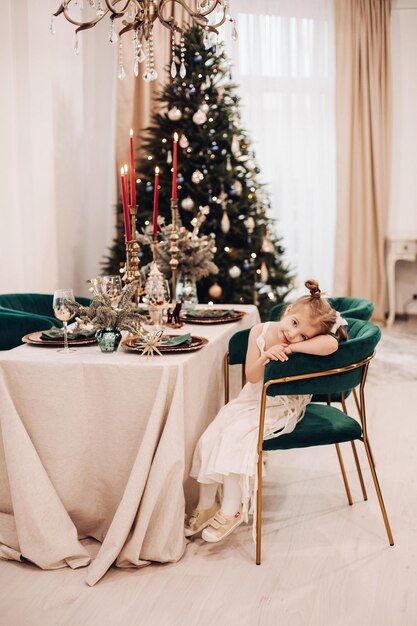 Jolie fille en belle robe est assise et attend le dîner de noël