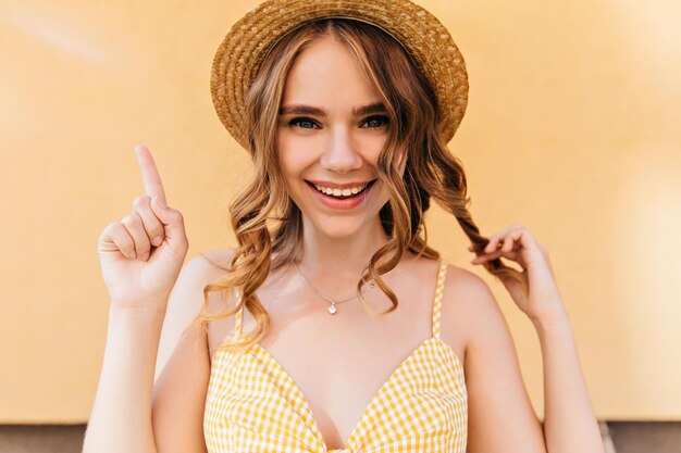 Jolie fille blonde aux grands yeux posant sur fond jaune Studio photo d'une femme caucasienne détendue s'amusant en journée d'été