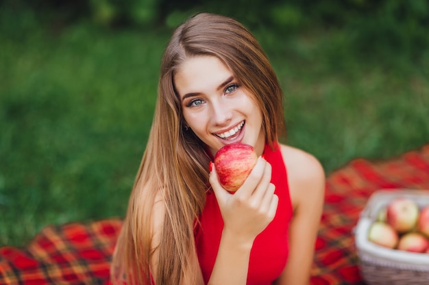 Jolie fille blonde souriante dans le parc avec apple