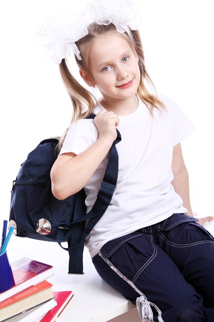 Jolie fille avec cartable assis sur le bureau