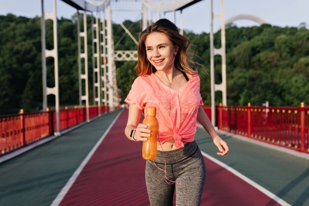 Jolie fille courir marathon avec le sourire. Tir en plein air d'un modèle féminin incroyable faisant du cardio le matin.