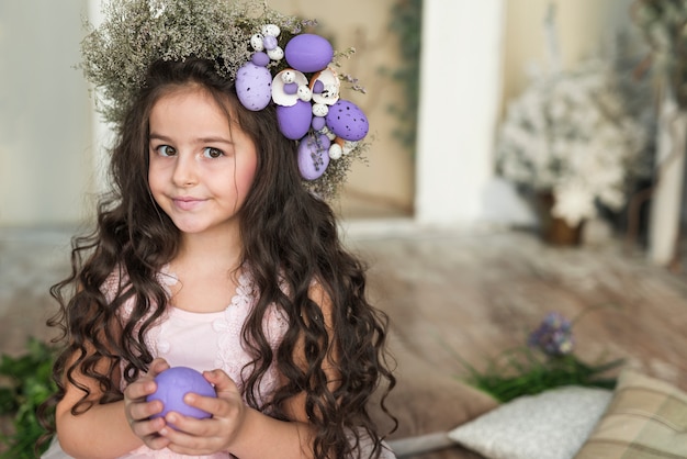 Photo gratuite jolie fille dans une couronne de fleurs avec oeuf de pâques