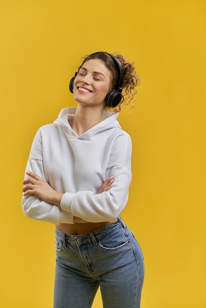 Jolie fille debout écoutant de la musique dans les écouteurs