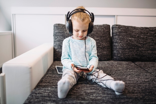 Photo gratuite jolie fille écoutant de la musique sur le canapé