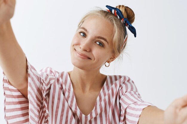 Jolie fille élégante posant contre le mur blanc