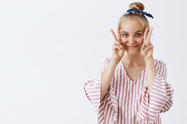 Jolie fille élégante posant contre le mur blanc