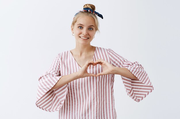 Jolie fille élégante posant contre le mur blanc