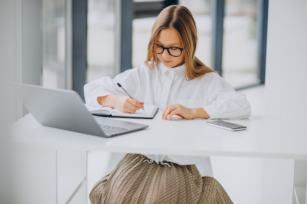 Jolie fille étudie sur l'ordinateur à la maison