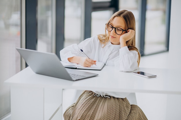 Jolie fille étudie sur l'ordinateur à la maison