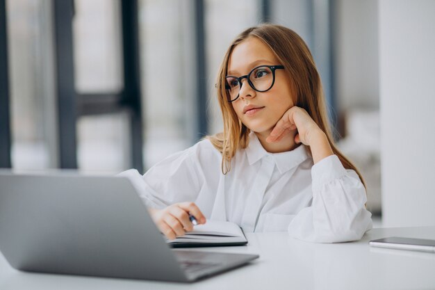 Jolie fille étudie sur l'ordinateur à la maison