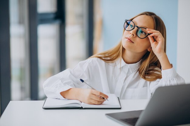 Jolie fille étudie sur l'ordinateur à la maison