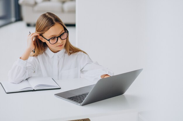 Jolie fille étudie sur l'ordinateur à la maison