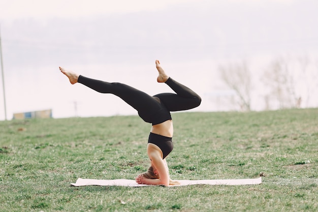 Jolie fille faisant du yoga dans un parc d'été