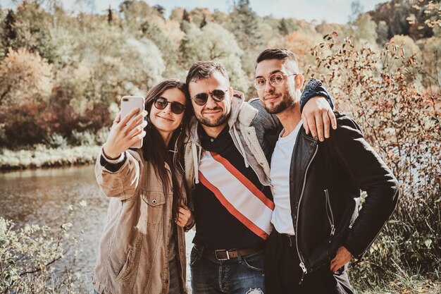 Jolie fille fait une photo d'elle-même et de ses amis au parc d'automne.