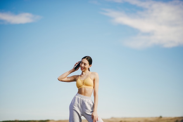 Jolie fille avec une formation par téléphone sur ciel bleu