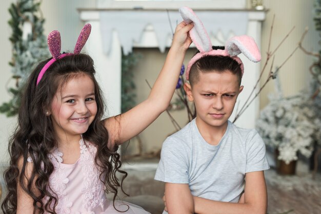 Jolie fille avec un garçon offensé dans des oreilles de lapin