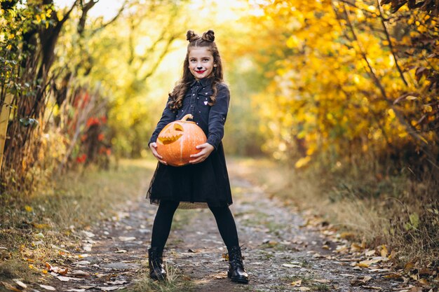 Jolie fille habillée en costume d'halloween à l'extérieur avec des citrouilles