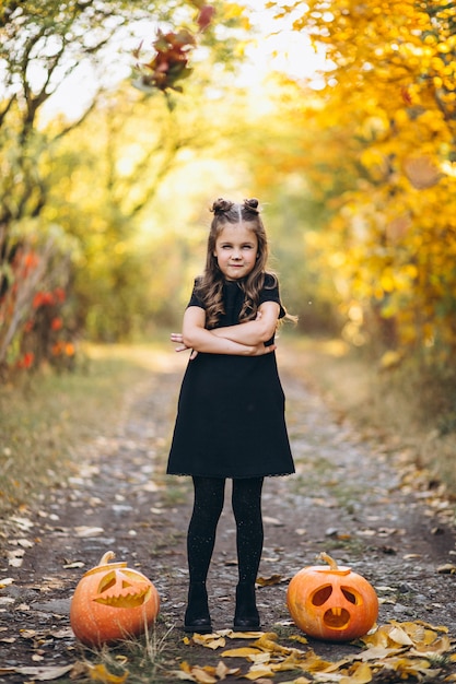 Jolie fille habillée en costume d'halloween à l'extérieur avec des citrouilles