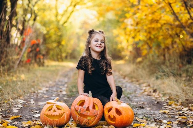 Jolie fille habillée en costume d'halloween à l'extérieur avec des citrouilles