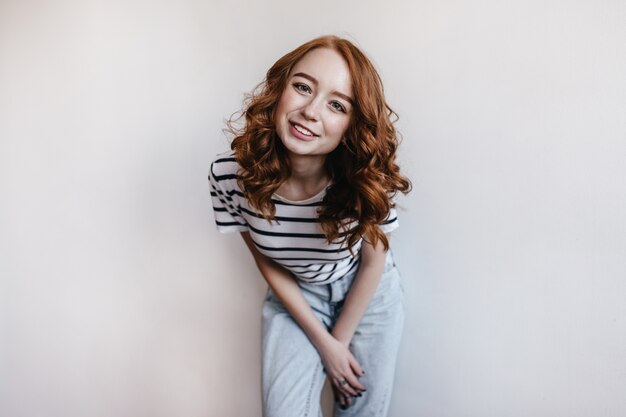 Jolie fille en jeans vintage posant avec le sourire sur son visage. Portrait de modèle féminin au gingembre en tenue de printemps à la mode.