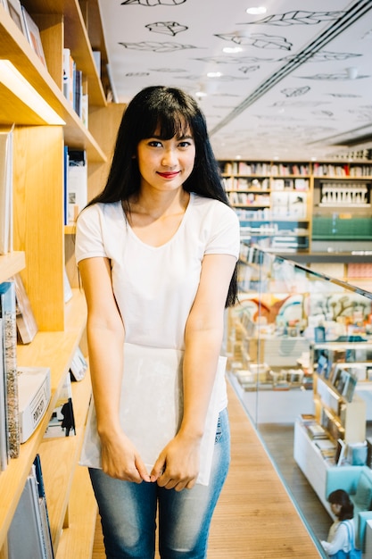 Jolie fille avec un livre dans la bibliothèque