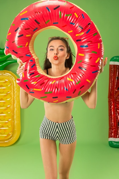 Jolie fille en maillot de bain posant au studio. Portrait d'été adolescent caucasien sur fond vert.