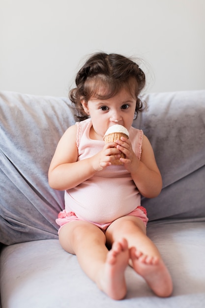 Jolie fille mangeant de la glace sur le canapé