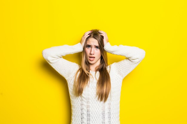 Jolie fille à la mode est confuse portant un large pull blanc sur jaune