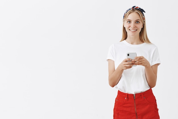 Jolie fille moderne à l'aide de téléphone portable et souriant