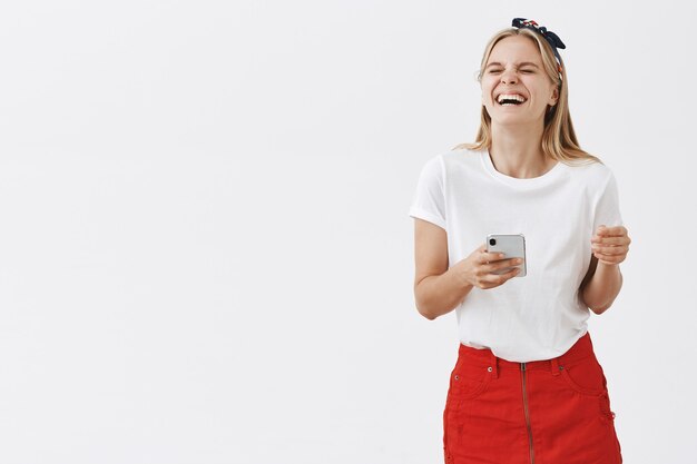 Jolie fille moderne à l'aide de téléphone portable et souriant
