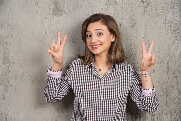 Une jolie fille montrant un signe de victoire à deux doigts.