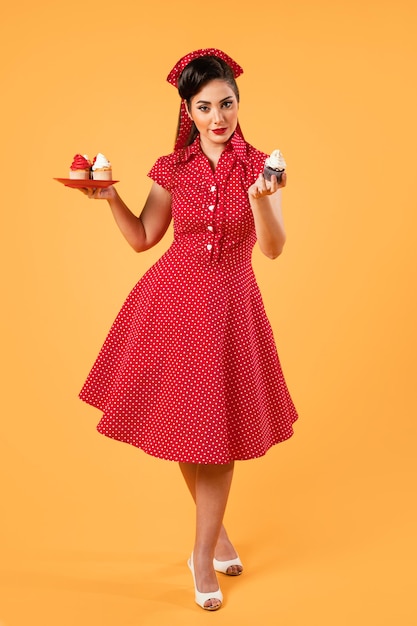 Jolie fille de pin-up posant avec des petits gâteaux