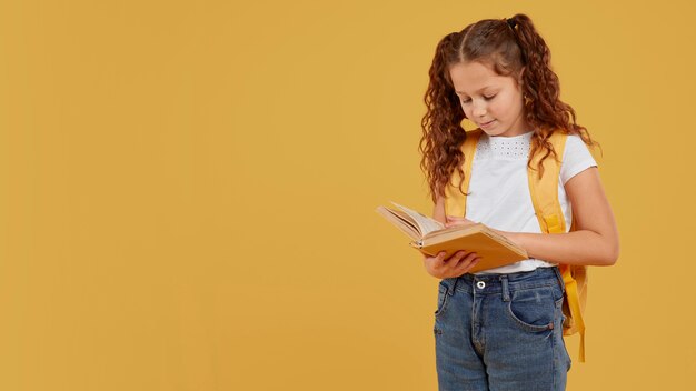 Jolie fille portant un sac à dos jaune et lit