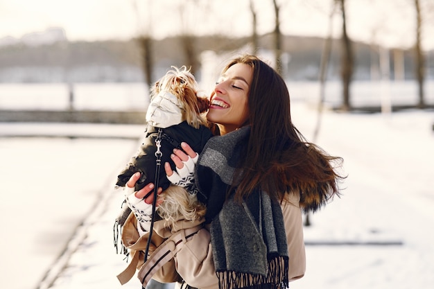 Jolie fille qui marche dans un parc d'hiver avec son chien