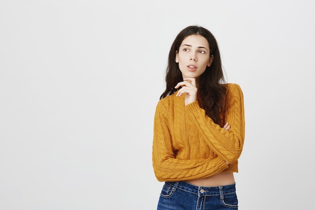 Jolie fille réfléchie pensant, prenant une décision, regardant dans le coin supérieur gauche et choisissant